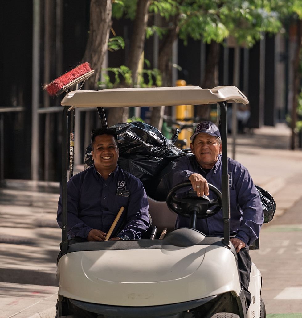 Two smiling sanitation workers in a gold cart